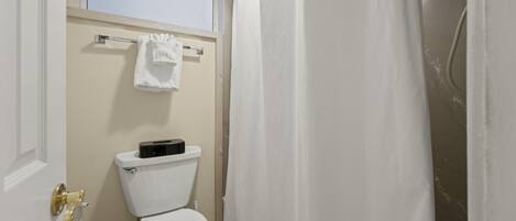 A bathroom with a toilet, a towel hanging on a rack, and a shower curtain.