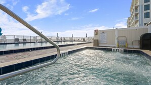 Una piscina con indicador de profundidad de 90 centímetros, un área de spa con un cartel que detalla las normas y vistas al océano.