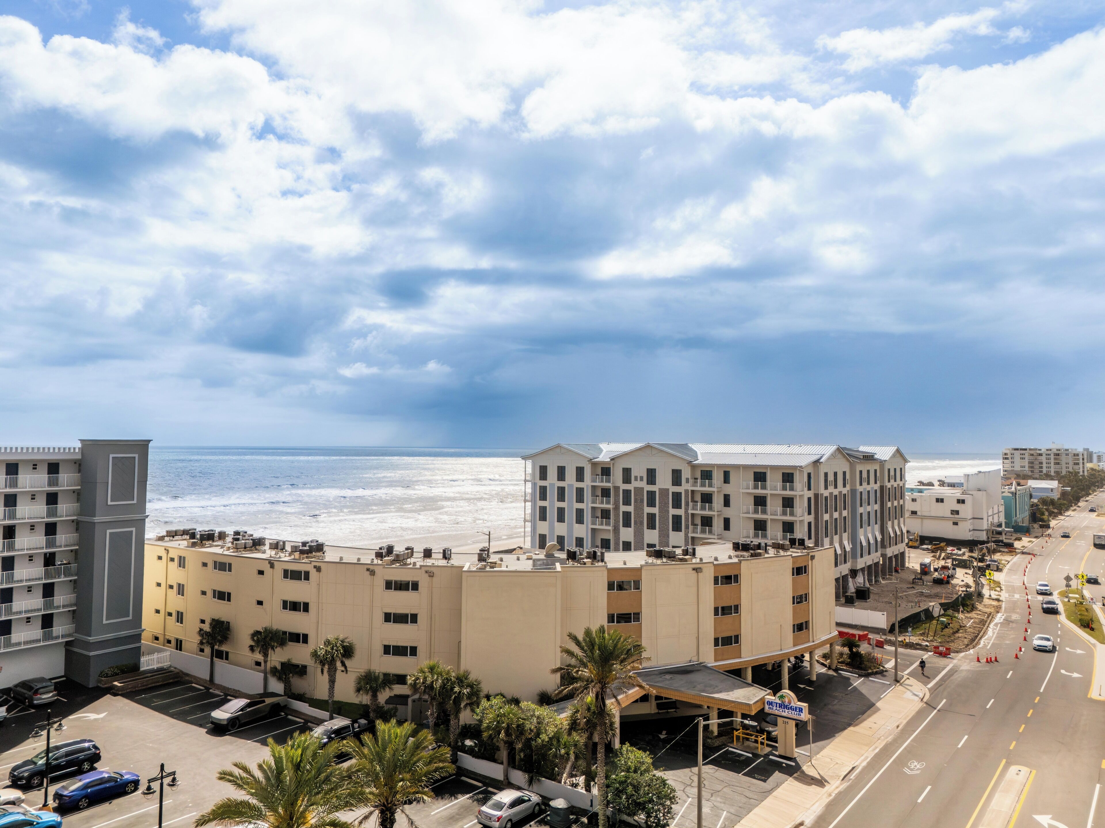 Un hotel con vista sulla spiaggia, diversi piani e un parcheggio.