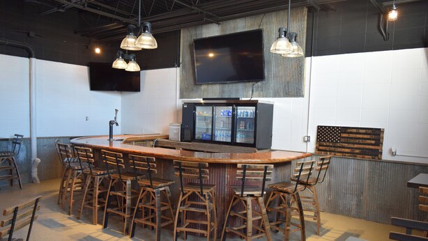 A bar area with a counter, stools, and a television mounted on the wall.