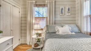 Una camera da letto con un letto, un comodino, una finestra con tende e decorazioni a parete.