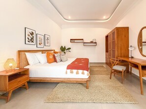 Ein Schlafzimmer mit Bett, Nachttisch, Lampe, Schreibtisch, Stuhl, Spiegel und Wandregalen.