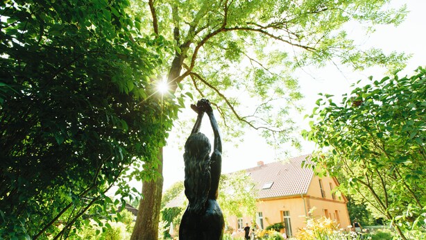 A statue of a woman in a garden with a house in the background. - Studio 6 - Träumerei - Quiet studio in the count's forester's lodge (Temmen-Ringenwalde)