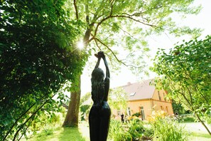 A statue of a woman in a garden with a house in the background. - Studio 6 - Träumerei - Quiet studio in the count's forester's lodge (Temmen-Ringenwalde)