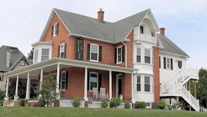 Une grande maison à deux étages, avec une enseigne « FPI » bien visible sur la façade, un porche abrité et un escalier menant à l’étage supérieur.