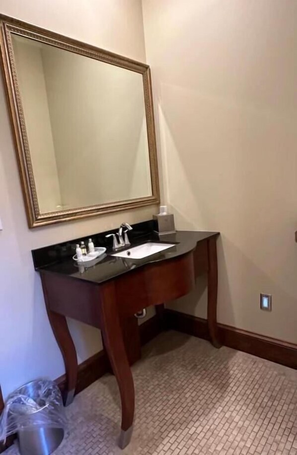 A bathroom with a wooden vanity, a large mirror, and a sink. - Heartland suites (Gettysburg)
