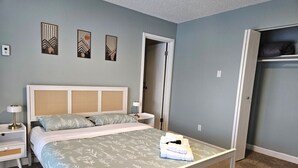 Un dormitorio con cama, mesitas de noche, un armario y una puerta.