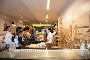 A restaurant interior with a long counter, staff serving, and a cityscape mural on the wall.