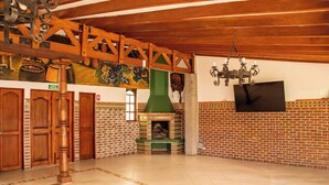Una habitación amplia con chimenea de ladrillo, puertas de madera y suelo de baldosas.