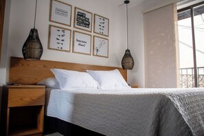 A neatly made bed with white linens, a wooden headboard, and a bedside table with a lamp. - Hotel Santamaria INN (La Ceja)