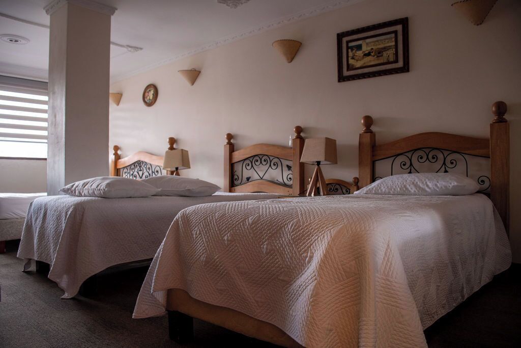 A hotel room with two single beds, each with a wooden headboard and a bedside lamp.