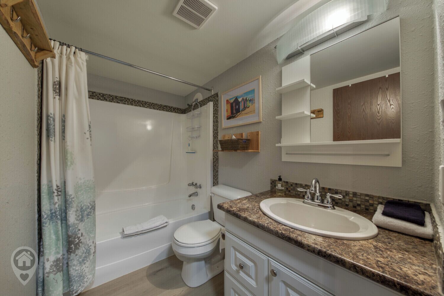 Une salle de bain équipée d’une douche, de toilettes, d’un lavabo et d’un miroir au-dessus du lavabo.