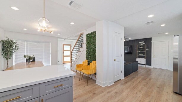 A modern kitchen with a white countertop, grey cabinets, and a wooden floor.