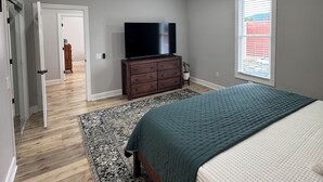 Una camera da letto con un letto, una ventola a soffitto, una televisione, un comò e una finestra.