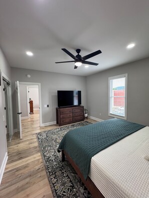 A bedroom with a bed, a ceiling fan, a TV, a dresser, and a window. - Retreat on Bridge Street - 3 Bed, 2 Bath Luxury Apartment (Tunkhannock)
