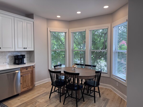 A kitchen with white cabinets, a coffee maker, and a dining table with chairs. - Retreat on Bridge Street - 3 Bed, 2 Bath Luxury Apartment (Tunkhannock)