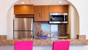 A compact kitchen with a stainless steel refrigerator, a microwave, and granite countertops. - 1-Bedroom Medano beach 5* resort ***HURRY***Only available March 14 to 21, 2026 (Cabo San Lucas)