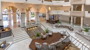 A spacious lobby with a central seating area, multiple staircases, and a view of the outdoors. - 1-Bedroom Medano beach 5* resort ***HURRY***Only available March 14 to 21, 2026 (Cabo San Lucas)