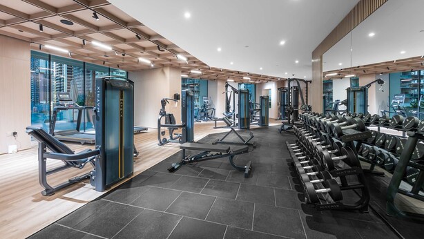 A modern gym with various exercise equipment, large windows, and a clean, organized layout. - Stayshort - Modern 1 Bedroom With Private Jacuzzi in JVC That Sleeps 2 (Dubai)