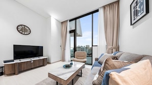 A modern living room with a flat-screen TV, a wooden entertainment unit, a marble coffee table, and a sofa with patterned cushions. - Stayshort - Modern 1 Bedroom With Private Jacuzzi in JVC That Sleeps 2 (Dubai)