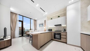 A modern kitchen with a central island, built-in appliances, and a large window. - Stayshort - Modern 1 Bedroom With Private Jacuzzi in JVC That Sleeps 2 (Dubai)