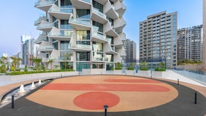 A modern building with a unique architectural design featuring multiple balconies and a rooftop garden. - Stayshort - Modern 1 Bedroom With Private Jacuzzi in JVC That Sleeps 2 (Dubai)