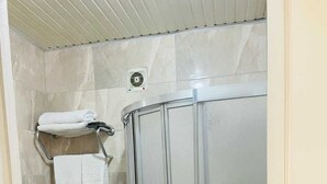 A bathroom with a toilet, a towel rack with folded towels, and a shower enclosure.