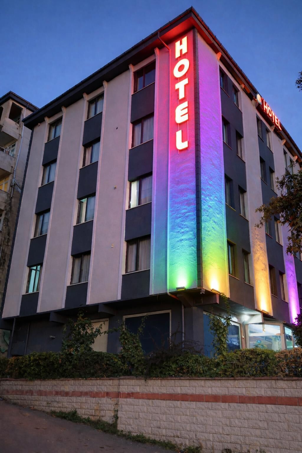 Un hotel de varios pisos con un letrero vertical que dice 'HOTEL' en luces brillantes.