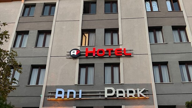 A hotel with a sign reading "HOTEL" and "ADJ PARK" on the facade.