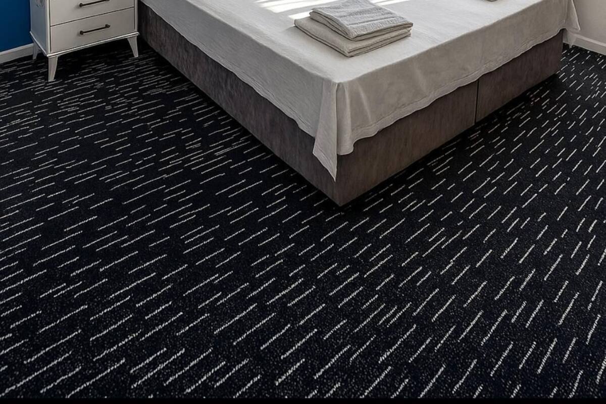 A hotel room with a large bed, two bedside tables, a nightstand, a window with curtains, and wall-mounted lights.
