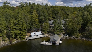 A lakeside cabin with a dock, surrounded by dense forest. - 9+ bed 7 bath cottage on Lake Muskoka (Bracebridge)