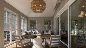 A sunlit room with large windows, a wooden floor, and a central seating area with a sofa and chairs. - 9+ bed 7 bath cottage on Lake Muskoka (Bracebridge)