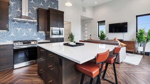 Une cuisine moderne avec des meubles en bois foncé, des appareils électroménagers en acier inoxydable et un grand îlot central doté de tabourets de bar.