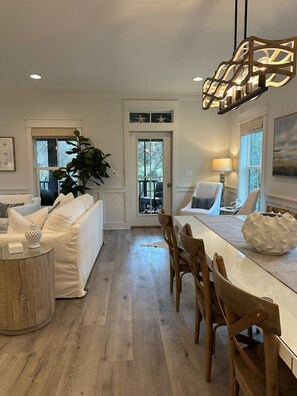 A modern kitchen with a dining area, wooden flooring, and a view through a glass door. - 30A Luxury Beach Cottage | Golf Cart | Bikes (Seacrest)