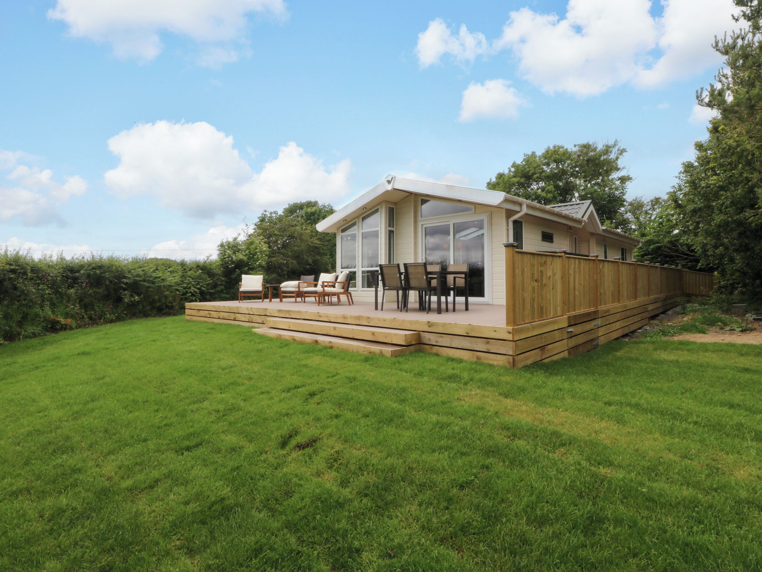 Een modern huis met een terras, tuinmeubilair en een groot raam.