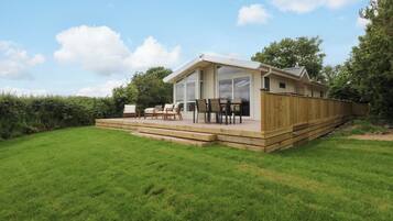 Een modern huis met een terras, tuinmeubilair en een groot raam.