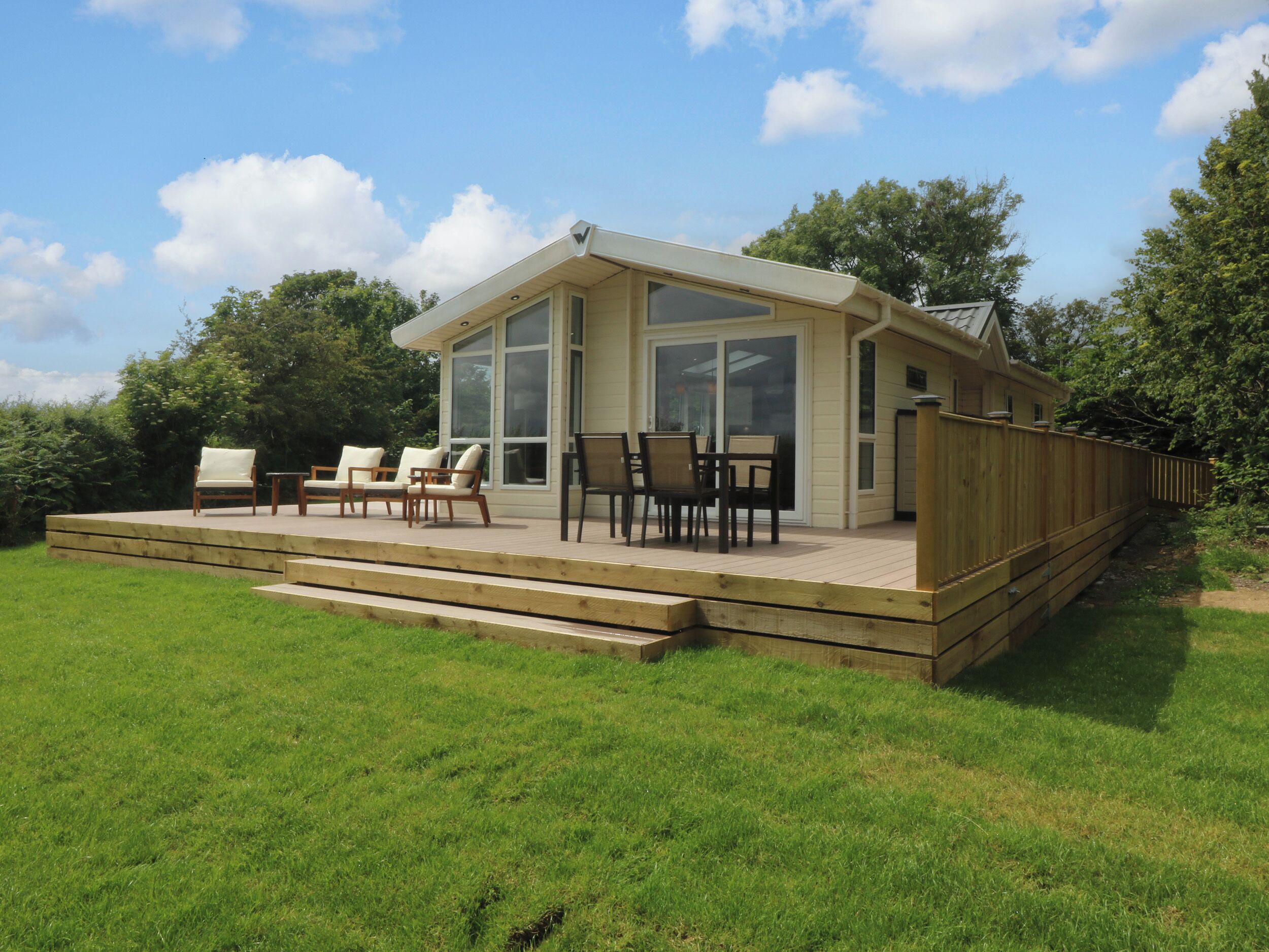A house with a deck, outdoor seating, and a large glass door.