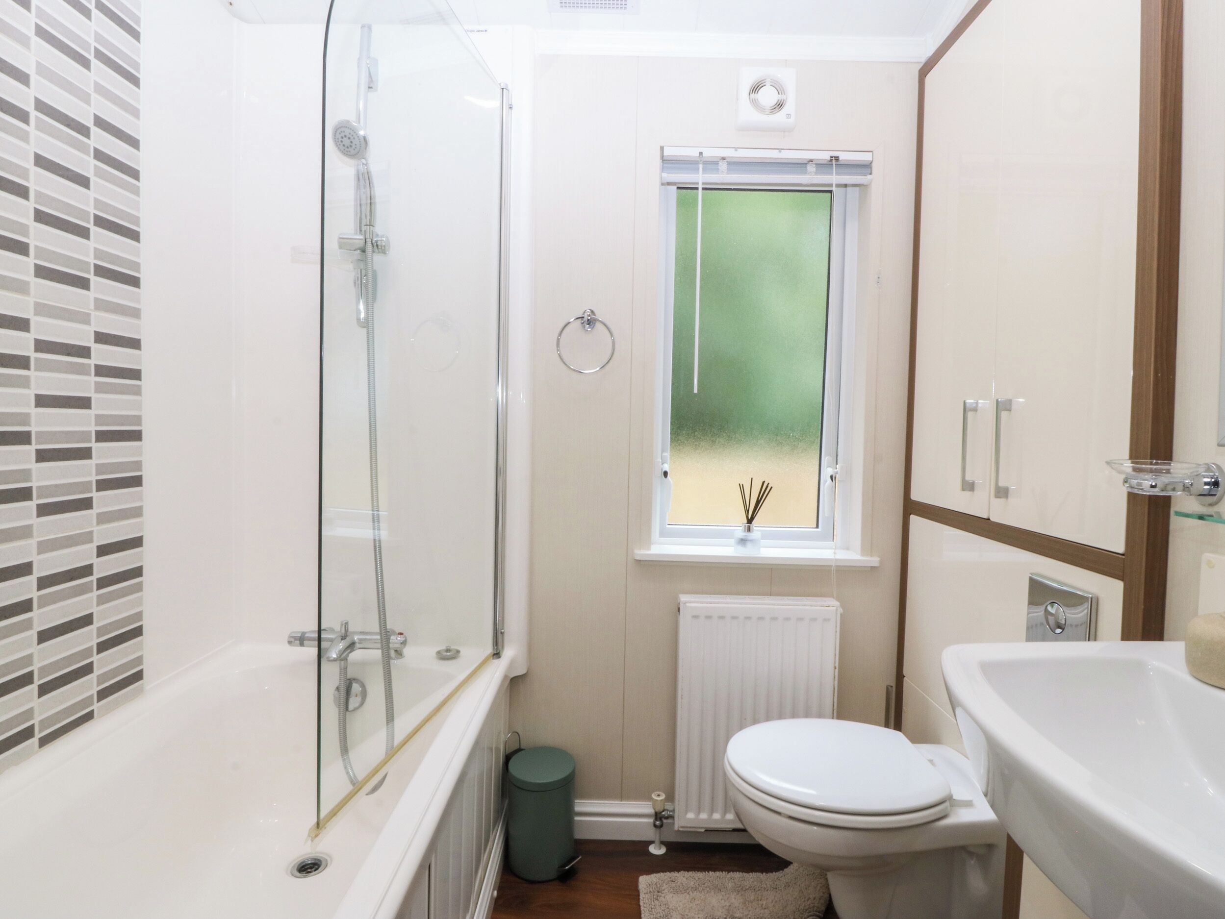 Une salle de bain avec une douche à parois de verre, des toilettes, un lavabo et une fenêtre donnant sur un beau paysage.