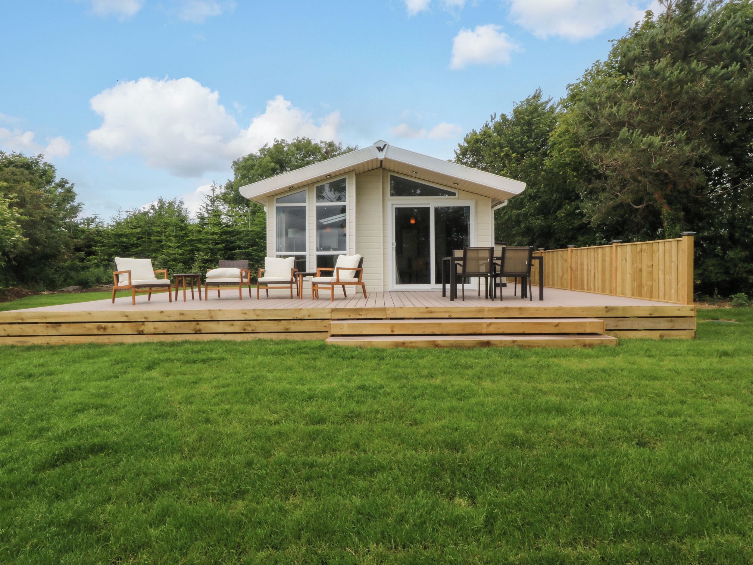 A house with a deck, outdoor seating, and a large window.