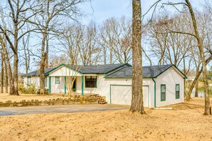 Einbungalow mit Garage, umgeben von Bäumen und sandigem Boden.