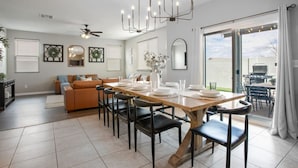 A modern dining area with a wooden table set for six, surrounded by black chairs. - Spacious 5BD with Pool Table (North Las Vegas)
