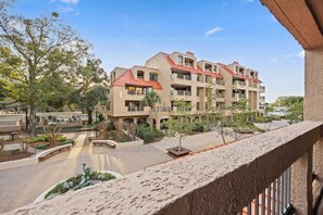 A multi-story hotel with balconies, a landscaped courtyard, and a clear sky. - Marina View Retreat at Shelter Cove Walk to Dining (Hilton Head Island)