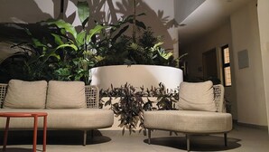 Un interior modern amb un sofà, una jardiniera amb diverses plantes i una finestra circular.