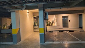 Un pàrquing amb sòls de formigó, places d'aparcament senyalitzades i una zona central d'ascensors.