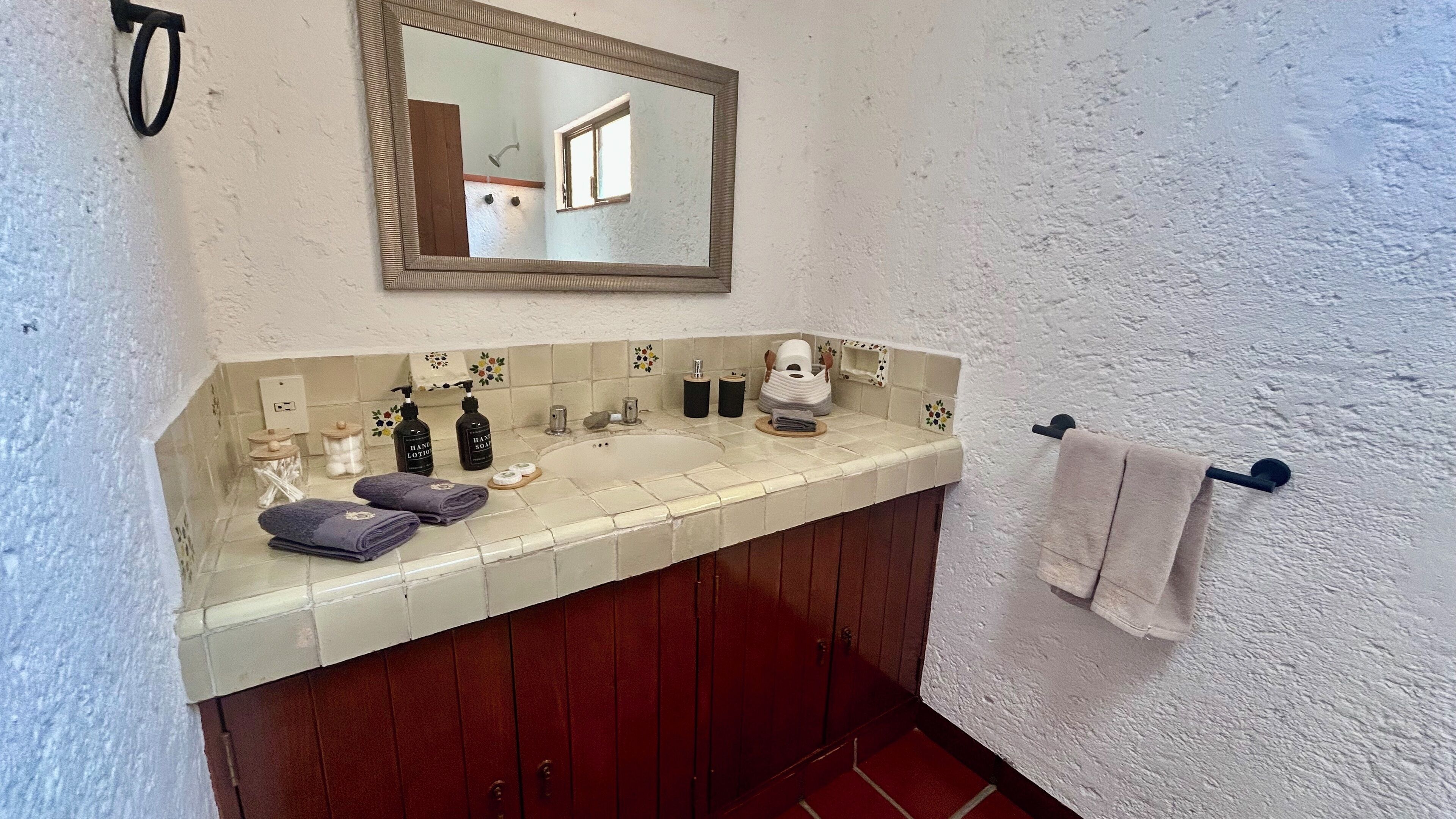 A bathroom with a sink, mirror, and towel rack.