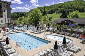 Un espace piscine avec des chaises longues, un toboggan et une vue sur un paysage verdoyant.