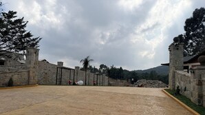 A paved courtyard with stone walls and a view of a mountainous landscape.