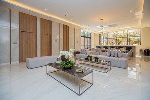 A modern living room with a sofa, two coffee tables, and a decorative plant arrangement. - Flat c/ Piscina e Academia na Chácara Klabin (São Paulo)