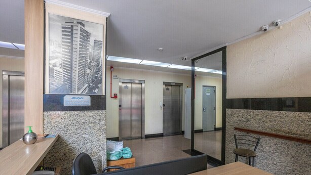 A modern office space with a reception desk, two elevators, and a glass partition. - Apartamento c 2 Quartos no Centro Histórico (Porto Alegre)