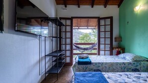 A room with two beds, a hammock, a wooden staircase, and a view of greenery outside. - Casa com fogão a lenha para 7 | Vale das Videiras (Itaipava, Petropolis)